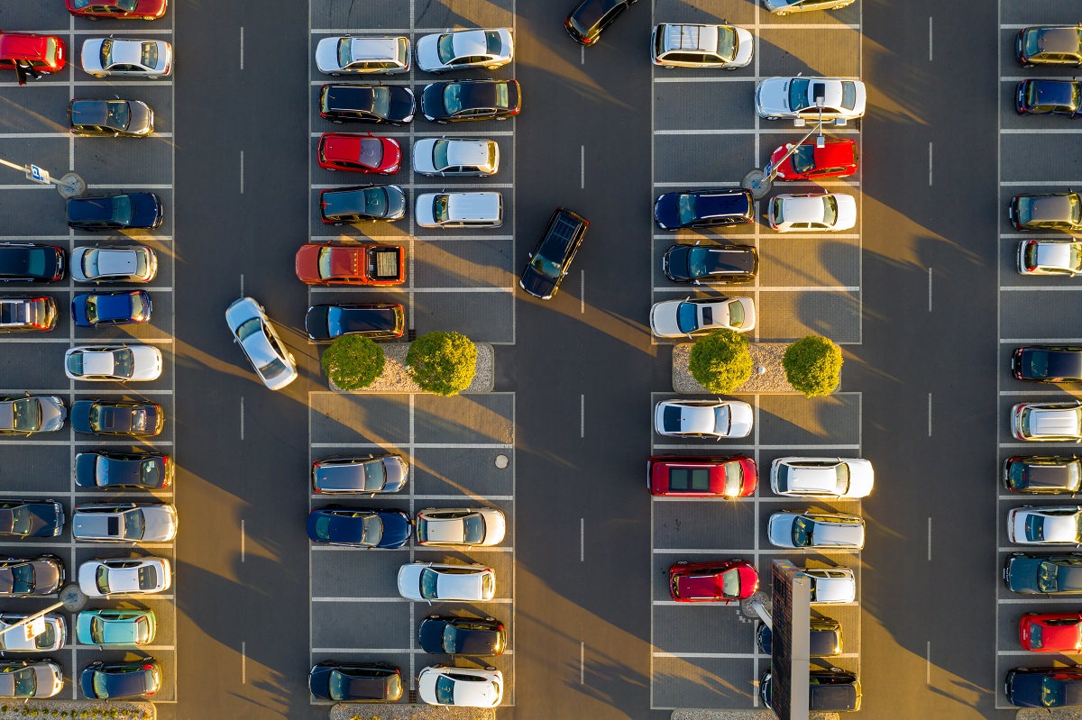 Top down view from drone on mall parking with many cars.